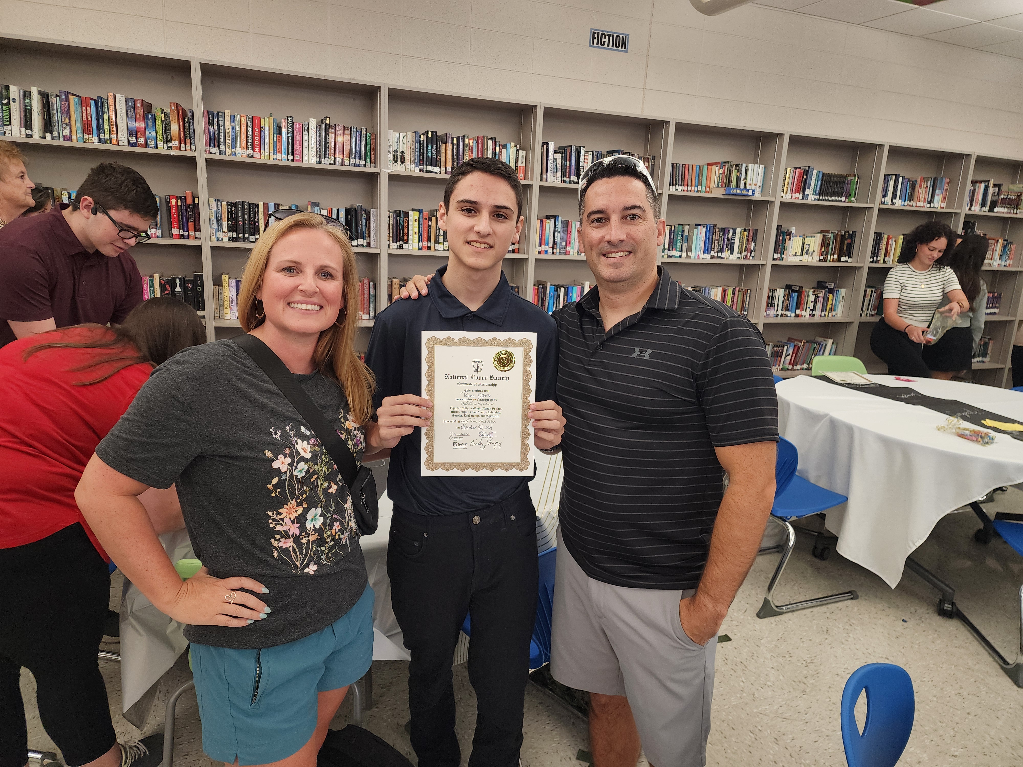 Student holding National Honor Society certificate with parents