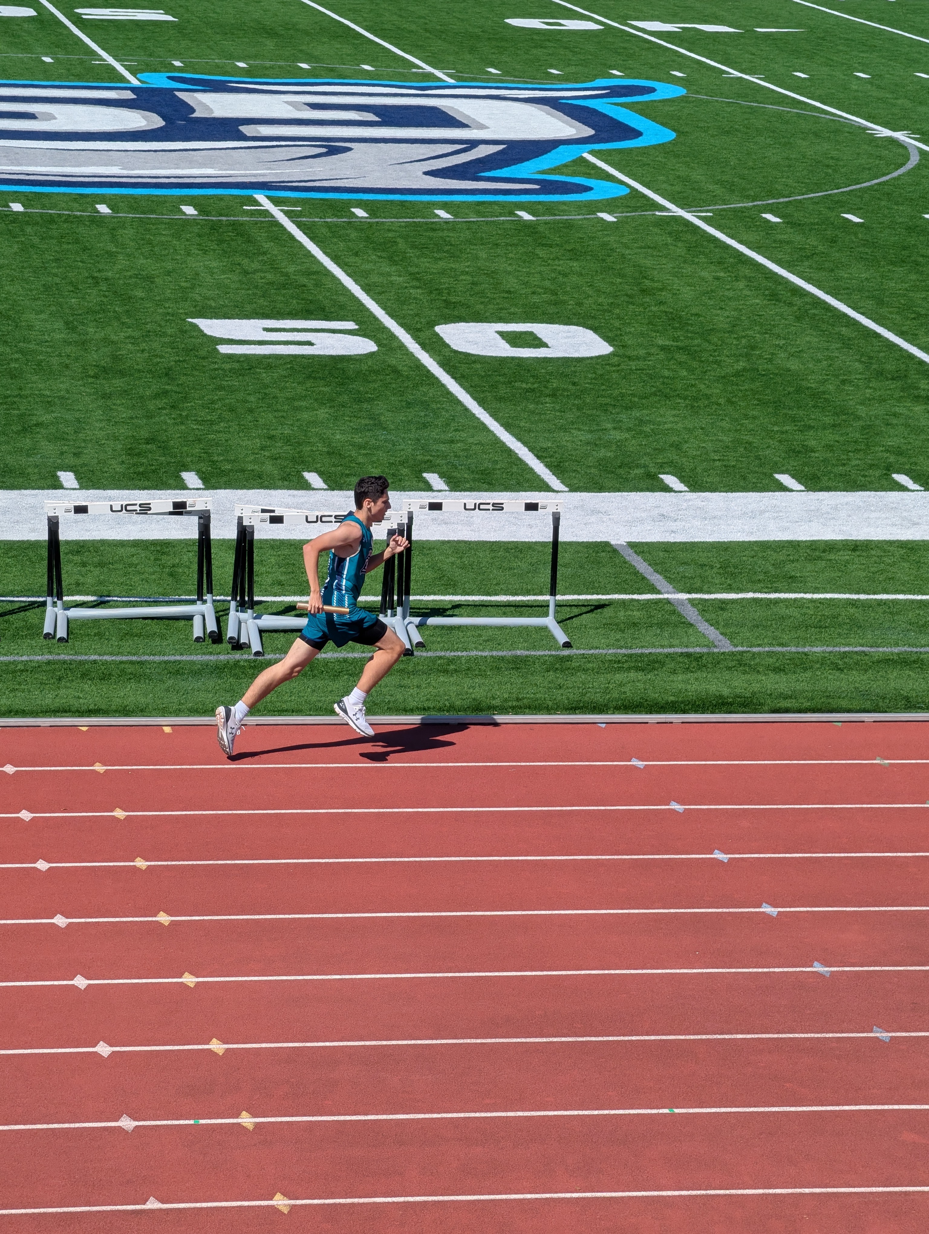 Male athlete running on track during relay race